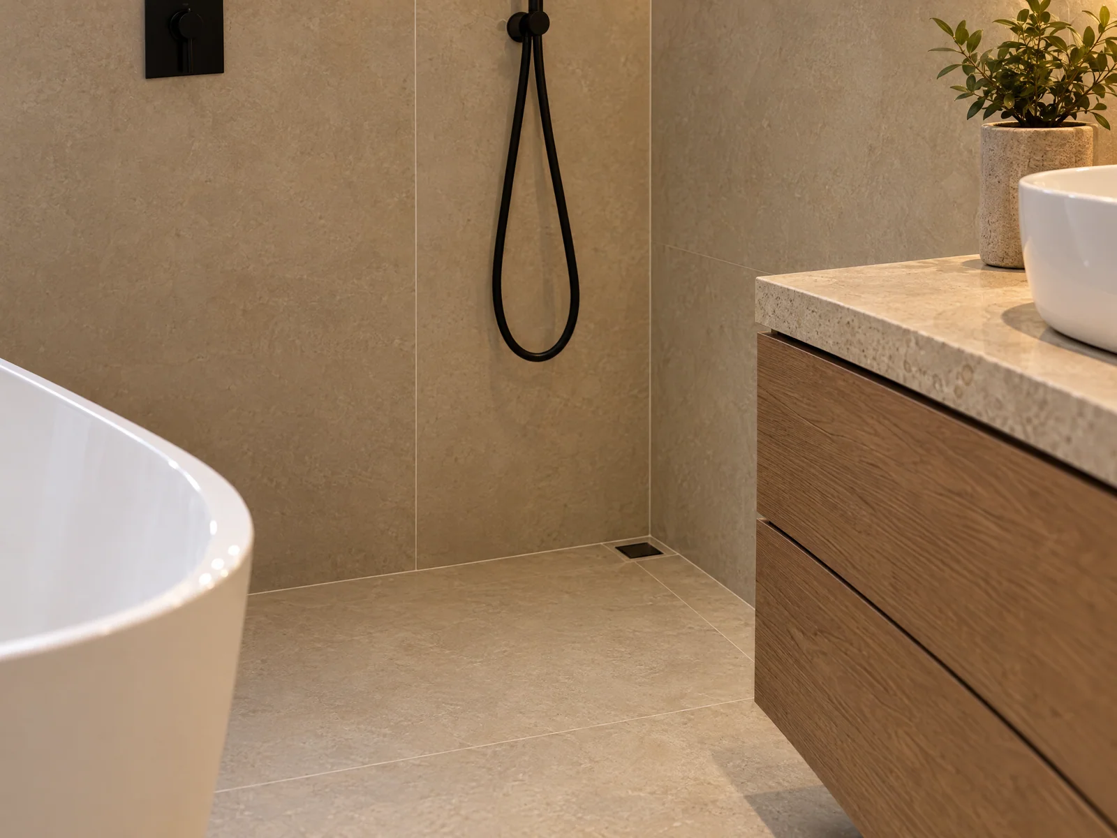 Large-format stone-effect tiles meeting the shower drain and oak vanity